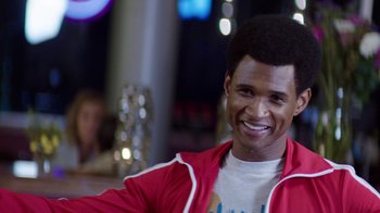 Movie still from “Hands of Stone” (2016), directed by Jonathan Jakubowicz – A man in a red jacket smiling for the camera; Close Up shot, Over the shoulder angle
