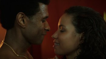 Movie still from “Hands of Stone” (2016), directed by Jonathan Jakubowicz – A man and a woman face to face in front of a red wall; Close Up shot, Over the shoulder angle