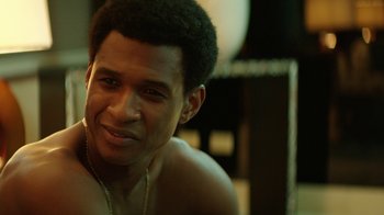 Movie still from “Hands of Stone” (2016), directed by Jonathan Jakubowicz – A person smiling for the camera; Close Up shot, Over the shoulder angle