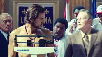 Movie still from “Hands of Stone” (2016), directed by Jonathan Jakubowicz – A group of men standing around a scale; Medium shot, Over the shoulder angle
