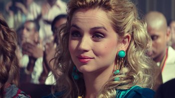 Movie still from “Hands of Stone” (2016), directed by Jonathan Jakubowicz – A woman with blonde hair wearing turquoise jewelry; Close Up shot, Over the shoulder angle