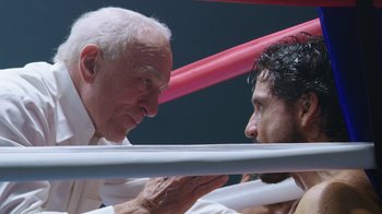Movie still from “Hands of Stone” (2016), directed by Jonathan Jakubowicz – Two men in a boxing ring talking to each other; Close Up shot, Low angle