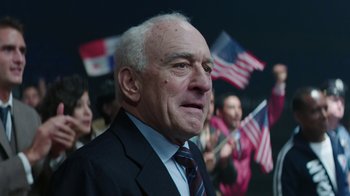 Movie still from “Hands of Stone” (2016), directed by Jonathan Jakubowicz – An older man in a suit and tie with other people in the background; Close Up shot, Low angle