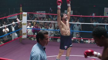 Movie still from “Hands of Stone” (2016), directed by Jonathan Jakubowicz – A man in a boxing ring raising his hands in the air; Wide shot, Low angle