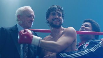 Movie still from “Hands of Stone” (2016), directed by Jonathan Jakubowicz – A man in a boxing ring getting ready for a fight; Medium shot, Over the shoulder angle