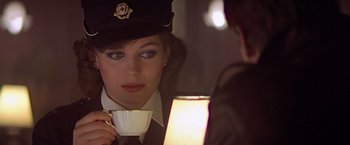 Movie still from “Hanover Street” (1979), directed by Peter Hyams – A woman holding a coffee cup while sitting next to a man; Close Up shot, Over the shoulder angle