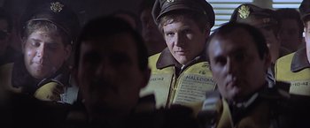 Movie still from “Hanover Street” (1979), directed by Peter Hyams – A man in a yellow jacket and a brown hat; Close Up shot, Over the shoulder angle