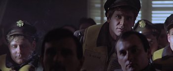 Movie still from “Hanover Street” (1979), directed by Peter Hyams – A man wearing a hat is looking at a camera; Close Up shot, Over the shoulder angle