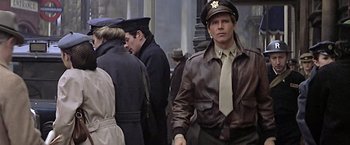 Movie still from “Hanover Street” (1979), directed by Peter Hyams – A man in a uniform and hat standing next to other men; Medium shot, Over the shoulder angle