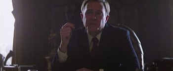 Movie still from “Hanover Street” (1979), directed by Peter Hyams – An older man wearing a suit and tie holding a pen; Close Up shot, Low angle