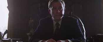 Movie still from “Hanover Street” (1979), directed by Peter Hyams – A man in a suit and tie with a pipe in his mouth; Close Up shot, Low angle