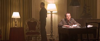 Movie still from “Hanover Street” (1979), directed by Peter Hyams – A man sitting at a desk in front of a lamp; Medium shot, Low angle