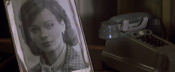 Movie still from “Hanover Street” (1979), directed by Peter Hyams – An old photo of a woman is being held up by a light; Extreme Close Up shot, Over the shoulder angle