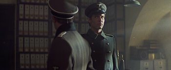 Movie still from “Hanover Street” (1979), directed by Peter Hyams – Two men in military uniforms stand next to each other; Medium shot, Over the shoulder angle