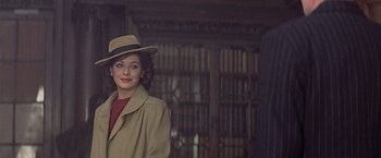Movie still from “Hanover Street” (1979), directed by Peter Hyams – A woman wearing a hat and a trench coat in a library; Medium shot, Over the shoulder angle