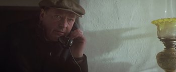 Movie still from “Hanover Street” (1979), directed by Peter Hyams – An older man talking on a phone while wearing a hat; Close Up shot, Low angle