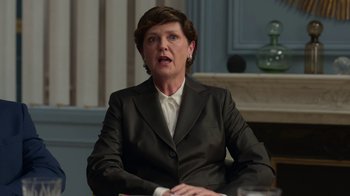 Movie still from “Emily in Paris” (2020), created by Darren Star – A woman wearing a suit sitting in front of a table; Medium shot, Low angle