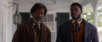 Movie still from “Harriet” (2019), directed by Kasi Lemmons – Two men standing next to each other in front of a window; Medium shot, Over the shoulder angle