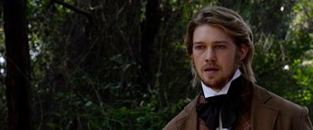 Movie still from “Harriet” (2019), directed by Kasi Lemmons – A man with long blonde hair wearing a brown jacket and a bow tie; Close Up shot, Over the shoulder angle