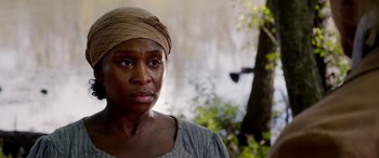 Movie still from “Harriet” (2019), directed by Kasi Lemmons – A woman with a head scarf is standing in front of a tree; Close Up shot, Over the shoulder angle