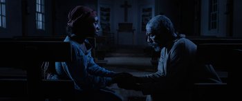 Movie still from “Harriet” (2019), directed by Kasi Lemmons – A man and a woman shaking hands in a dark room; Medium shot, High angle