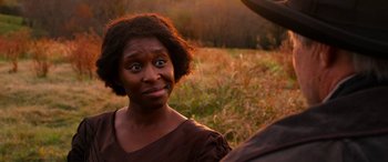 Movie still from “Harriet” (2019), directed by Kasi Lemmons – An african american woman in a brown dress looking at the camera; Close Up shot, Over the shoulder angle