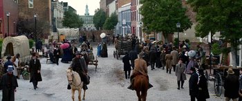 Movie still from “Harriet” (2019), directed by Kasi Lemmons – A group of people walking down a street on horses and carriages; Extreme Wide shot, High angle