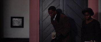Movie still from “Harriet” (2019), directed by Kasi Lemmons – A man in a brown suit is standing in front of a door; Medium shot, Low angle