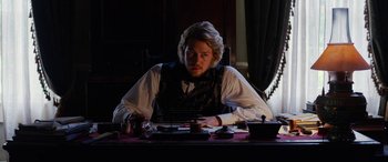 Movie still from “Harriet” (2019), directed by Kasi Lemmons – A man sitting at a table in front of a laptop; Medium shot, Low angle