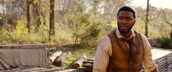 Movie still from “Harriet” (2019), directed by Kasi Lemmons – A man sitting on top of a wooden bench in the woods; Close Up shot, Over the shoulder angle