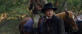 Movie still from “Harriet” (2019), directed by Kasi Lemmons – A man with a beard wearing a black hat; Medium shot, Over the shoulder angle