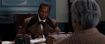 Movie still from “Harriet” (2019), directed by Kasi Lemmons – A man sitting at a table in front of an open briefcase; Close Up shot, Over the shoulder angle