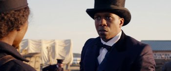 Movie still from “Harriet” (2019), directed by Kasi Lemmons – A man wearing a top hat standing in front of other men; Close Up shot, Over the shoulder angle