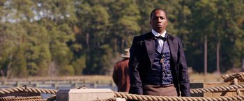 Movie still from “Harriet” (2019), directed by Kasi Lemmons – A man standing on top of a dock wearing a suit; Medium shot, Over the shoulder angle