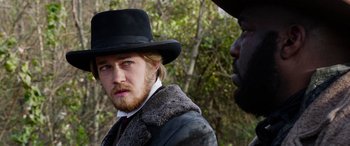 Movie still from “Harriet” (2019), directed by Kasi Lemmons – A man wearing a black hat and a fur coat; Close Up shot, Over the shoulder angle