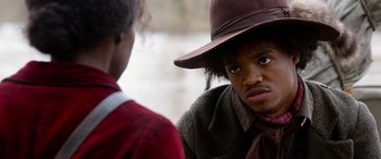 Movie still from “Harriet” (2019), directed by Kasi Lemmons – A young man wearing a brown hat and a red tie; Close Up shot, Over the shoulder angle