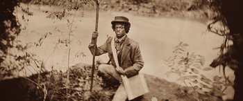 Movie still from “Harriet” (2019), directed by Kasi Lemmons – An old photo of a man holding a stick and a bag; Medium shot, High angle