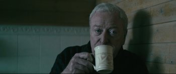 Movie still from “Harry Brown” (2009), directed by Daniel Barber – An older man holding a coffee mug in his hands; Close Up shot, Low angle