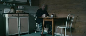 Movie still from “Harry Brown” (2009), directed by Daniel Barber – An older man sitting at a table with a cup of coffee; Wide shot, High angle