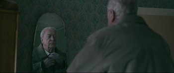 Movie still from “Harry Brown” (2009), directed by Daniel Barber – An older man looking at himself in the mirror; Medium shot, Over the shoulder angle