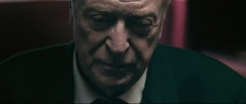 Movie still from “Harry Brown” (2009), directed by Daniel Barber – An older man wearing a suit and tie looking down; Close Up shot, Low angle