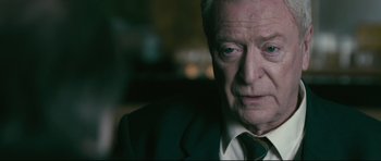 Movie still from “Harry Brown” (2009), directed by Daniel Barber – An older man wearing a suit and tie; Close Up shot, Over the shoulder angle