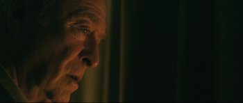 Movie still from “Harry Brown” (2009), directed by Daniel Barber – A man's face in a dark room; Close Up shot, Over the shoulder angle