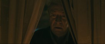 Movie still from “Harry Brown” (2009), directed by Daniel Barber – An older man looking out of a window at night; Close Up shot, Low angle