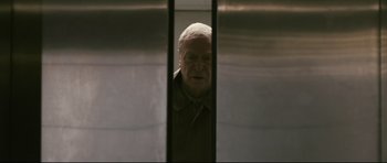 Movie still from “Harry Brown” (2009), directed by Daniel Barber – An older man looking out of an elevator window; Medium shot, Low angle