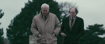 Movie still from “Harry Brown” (2009), directed by Daniel Barber – Two older men walking down the street in the rain; Medium shot, Low angle