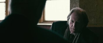 Movie still from “Harry Brown” (2009), directed by Daniel Barber – An older man sitting in an office chair in front of a window; Close Up shot, Over the shoulder angle