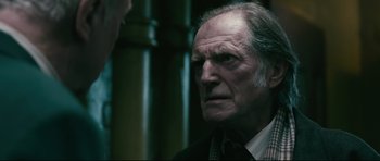 Movie still from “Harry Brown” (2009), directed by Daniel Barber – An older man wearing a suit and a tie; Close Up shot, Over the shoulder angle