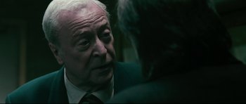 Movie still from “Harry Brown” (2009), directed by Daniel Barber – An older man wearing a suit and tie; Close Up shot, Over the shoulder angle