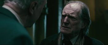 Movie still from “Harry Brown” (2009), directed by Daniel Barber – An older man wearing a suit and tie talking to a younger man; Close Up shot, Over the shoulder angle